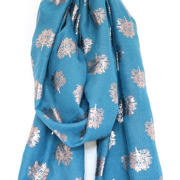 A teal coloured scarf with a print of leafless oak trees in gold foil dotted all over it