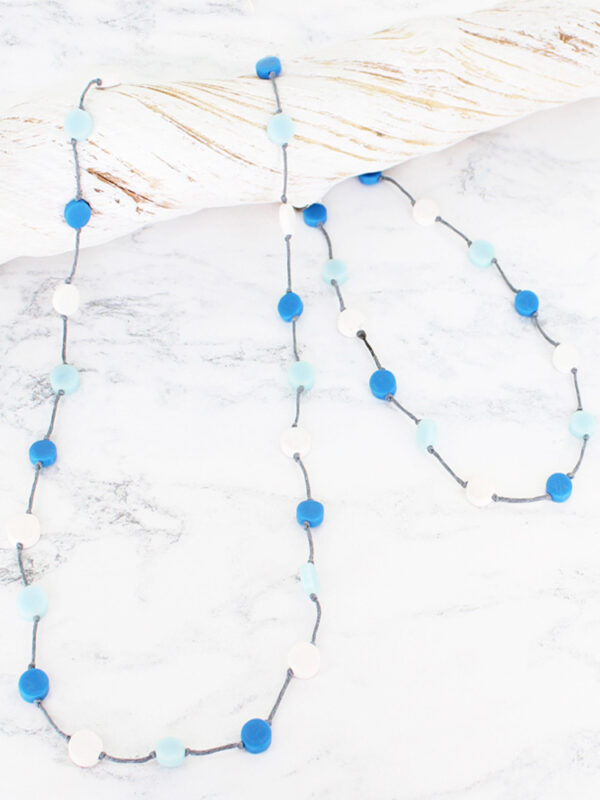 A long necklace made of tiny resin discs strung on a cord in shades of blue and white