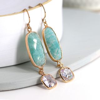 Aqua stone gold earrings with a crystal drop, hooked on the edge of a ceramic mug