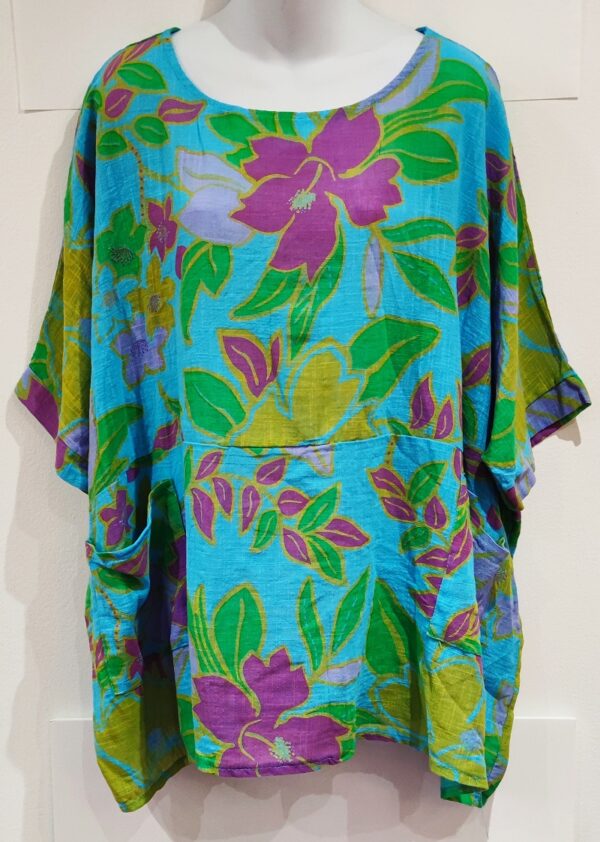 A turquoise cotton top with short sleeve and two patch pockets in a floral print in pink, yellow and green
