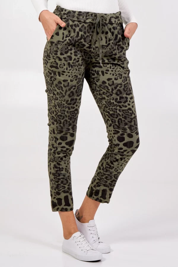 lady wearing a white top and leopard printed trousers, and white trainers, no background