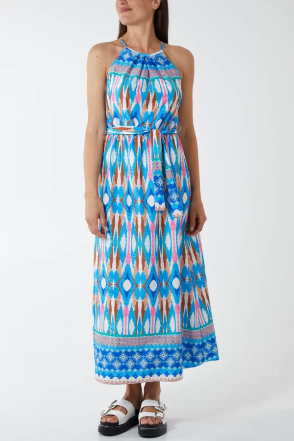 a girl against a white background wearing a diamond printed blue halter neck maxi dress