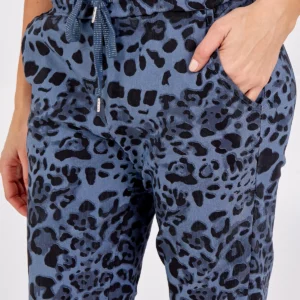 a girl with her hand in the pocket of leopard print denim blue trousers, with a white tee shirt