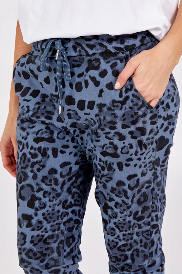 a girl with her hand in the pocket of leopard print denim blue trousers, with a white tee shirt
