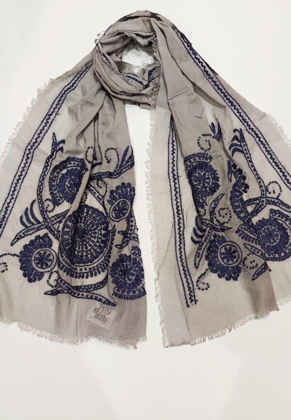A soft grey scarf with thick denim blue embroidery on two ends