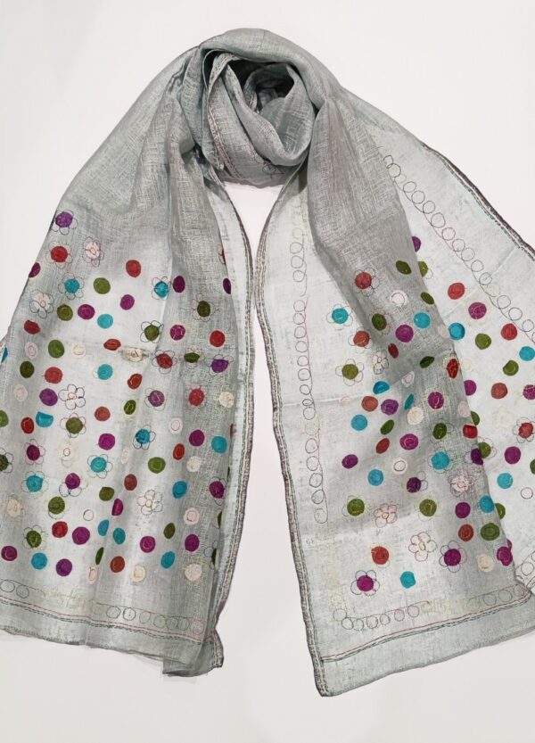 A pale mint coloured woven linen scarf, covered in multicoloured dots