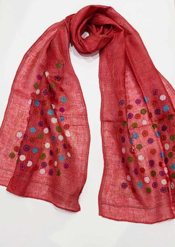 a woven linen scarf in a terracotta coulour covered in multicoloured little dots