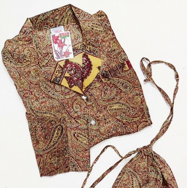 a golden paisley printed pyjama top lying on a white background with matching drawstring bag