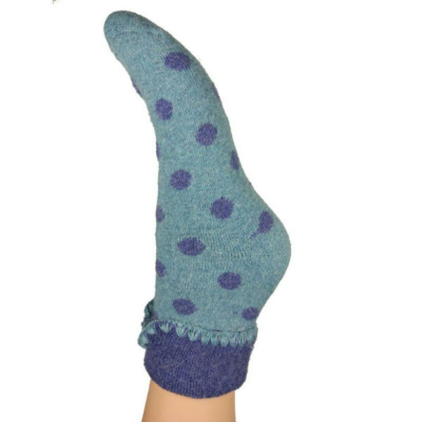 a picture of a single foot wearing a blue wool sock witha pattern of darker blue dots all over it