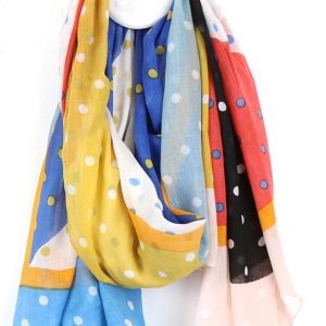 a cotton scarf looped around a wall hook in shades of red, blue, yellow and white with multicoloured dots all over it