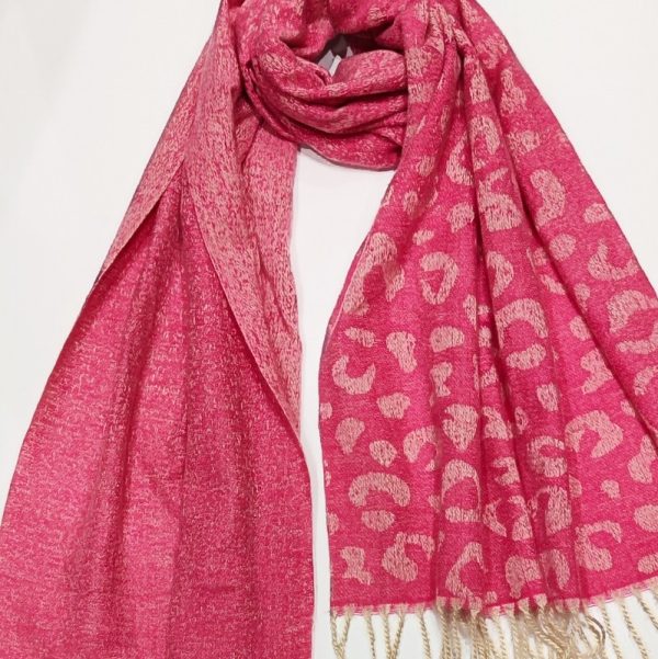 a two tone woven pink scarf ,one half is plain pink and the other has a leopard print design woven into it, with cream coloured tassles on a white background