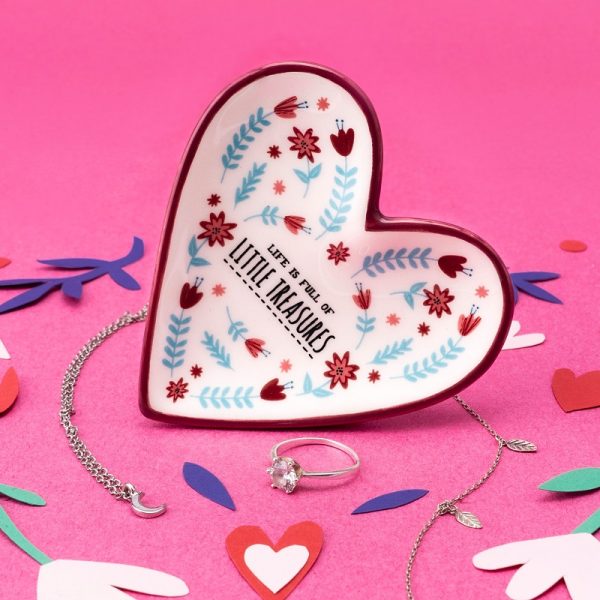a little heart shaped ceramic trinket dish with the slogan 'life is full of little treasures' painted on it, lying on a pink background with a silver chain and coloured confetti around it
