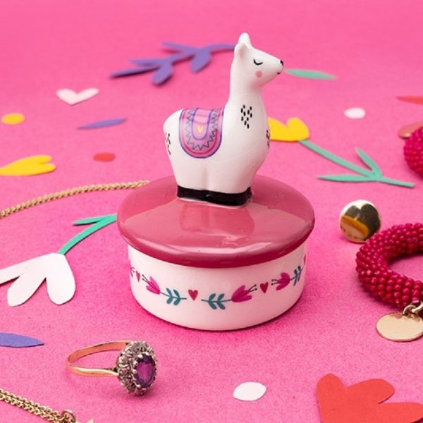 a tiny ceramic keepsake pot with a pink coloured lid with a little llama on the top, standing on a pink background with coloured confetti around it