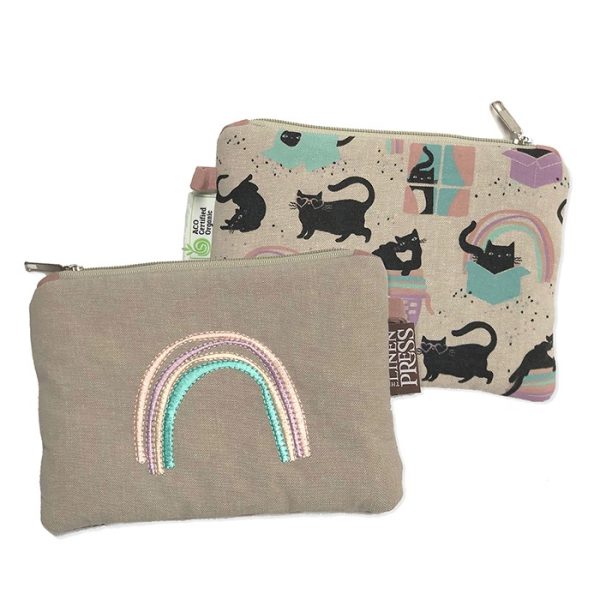a cotton cosmetic bag with an pastel coloured embroidered rainbow on one side and images of cats in different poses on the reverse side