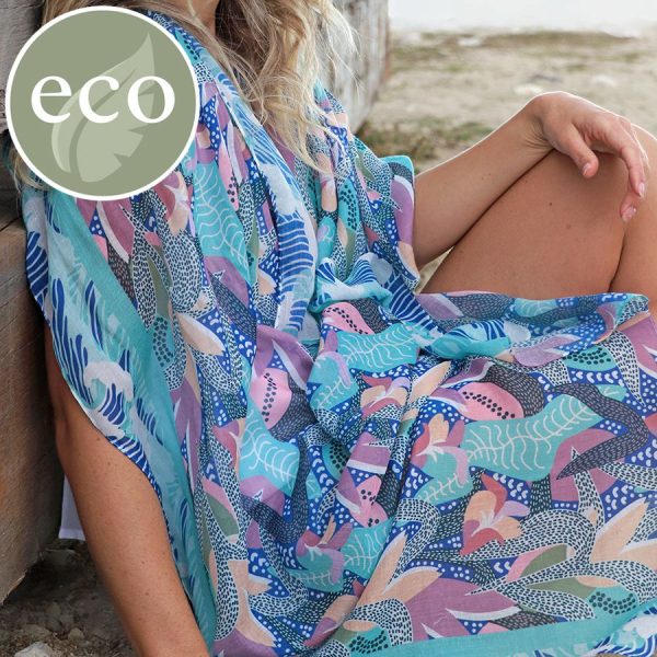 a blonde lady on the beach wrapped in a blue and lilac marine plant print scarf