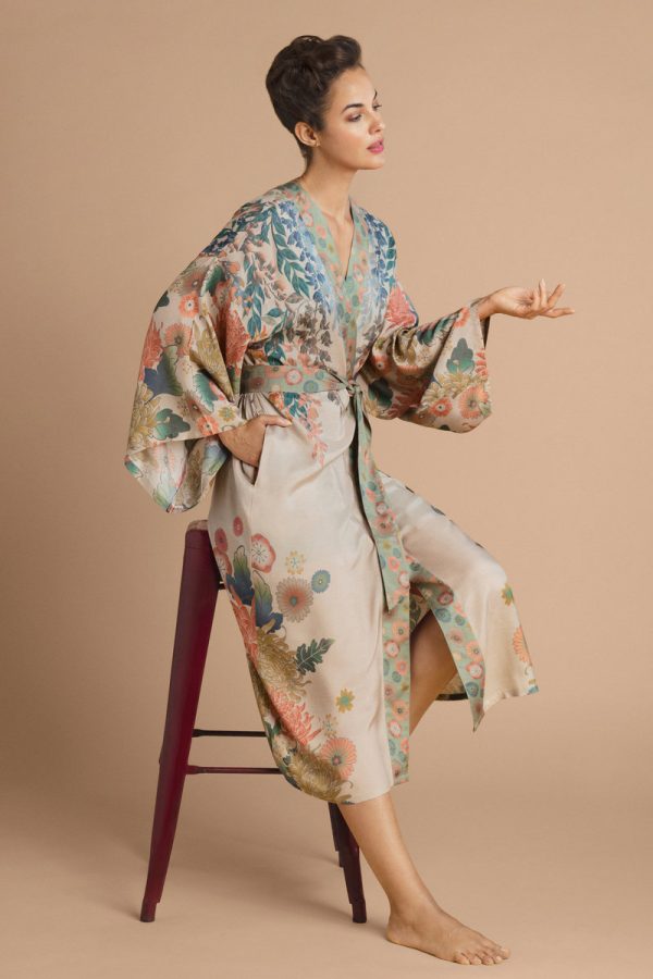 a girl sitting on a high stool wearing a coconut coloured long kimono with a print of trailing wisteria