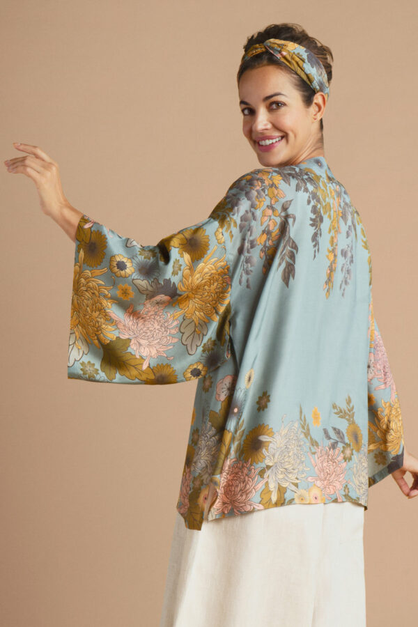 a girl wearing an ice blue kimono jacket with a trailing wisteria print in pinks and golds