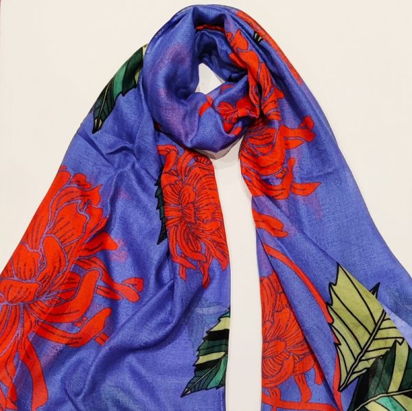 a deep blue scarf with a print of large red chrysanthamums and green leaves - shown twisted on a flat background