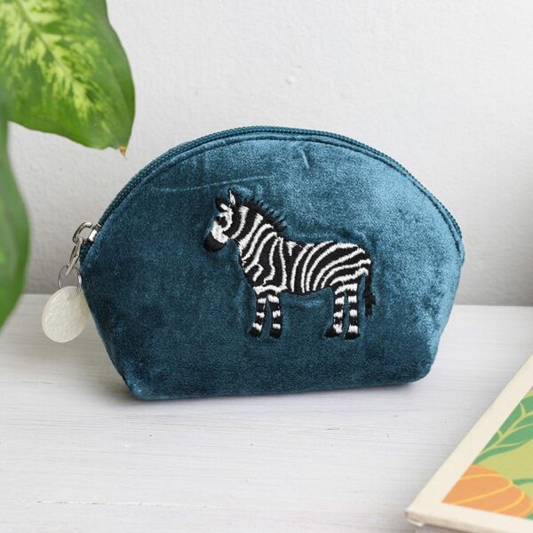 a teal blue velvet d shaped pouch with a black and white embroidered zebra on the front