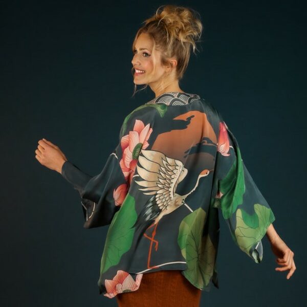 a dark coloured short kimono style jacket with a large print of a white crane amongst green oriental leaves and pink blooms