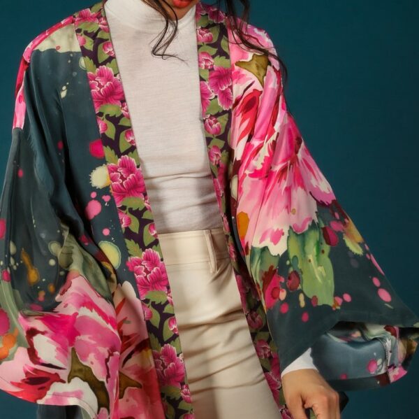 a dark coloured short kimono with a vibrant oversize peony flower print worn over a cream top and trousers