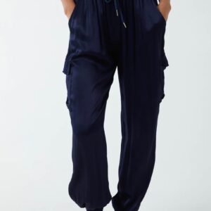 a pair of midnight navy satin cargo pants with two pockets on each side, an elasticated waistband and cuffs, worn with a white vest.