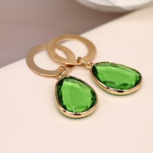 a faux gold hoop earring with a bright green crystal drop