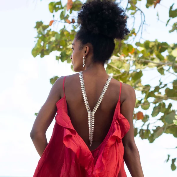 a silver zip style necklace shown worn down the back on a black girl in a red backless dress
