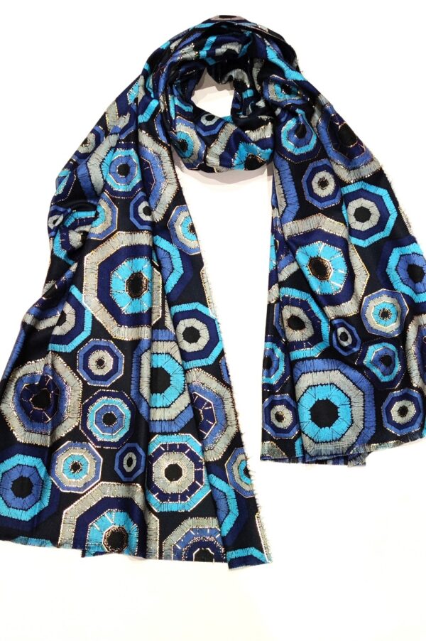 a foil print scarf shown twisted at the neck with a geometric geode design on it in shades of navy, blue and grey