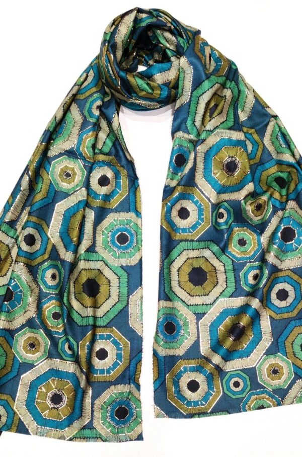 a pashmina style scarf with a print of geodes in shades of teal, khaki, turquoise and greens with a gold foil overprint